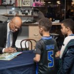 A man signing an autograph for two young boys.