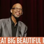 A man in a suit and glasses is smiling.