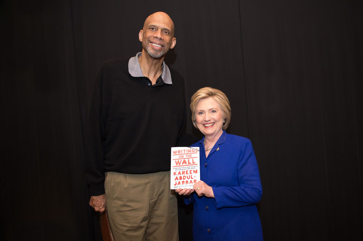A man and woman holding up a book.