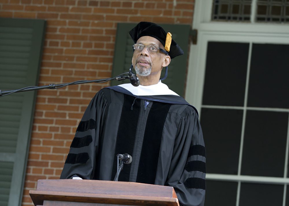 A man in graduation robes standing at the podium.