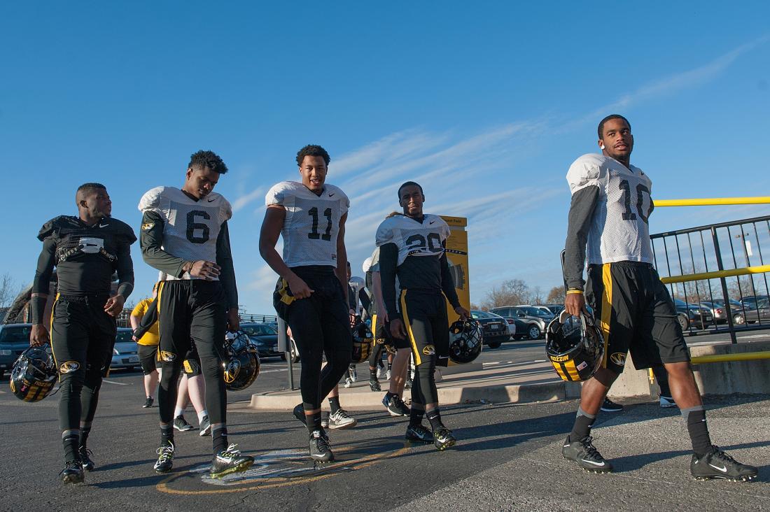 A group of football players walking on the street.
