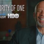 A man smiling for the camera in front of an hbo logo.
