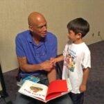 A man and boy are shaking hands over a book.