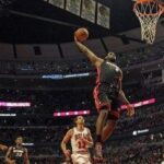 A basketball player is jumping in the air to dunk.