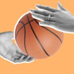 A basketball is being held by two hands.