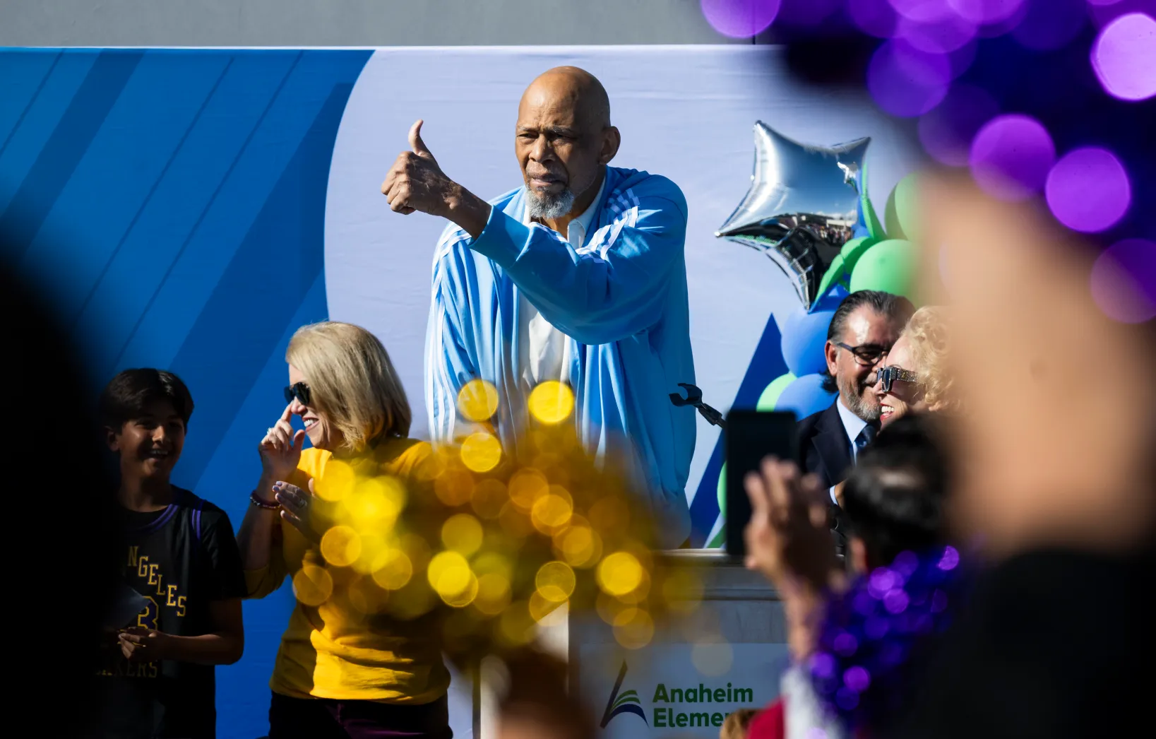 OCR-L-A2-Abdul-Jabbar-01-PB-1 Lakers legend Kareem Abdul-Jabbar gives the thumbs up as students cheer with pom-poms at Edison Elementary School in Anaheim, CA on Wednesday, November 19, 2025. Abdul-Jabbar announced a partnership between his Skyhook Foundation and the Orange County Department of Education’s Inside the Outdoors to expand environmental science STEM learning programs. More than 3,000 pairs of Adidas shoes and backpacks were donated to students in the Anaheim Unified School District. (Photo by Paul Bersebach, Orange County Register/SCNG)